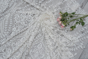 White wooden background with white spring flowers roses and lace ribbon. Happy womans day. The texture of lace on wooden background.