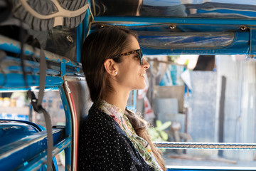 Woman backpacker traveling in public transport in Thailand. Songthaew are cheap way to travel...