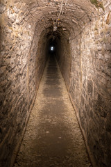 Dunkle gerade Höhle mit Licht am Ende des Tunnels als Metapher für Hoffnung und Durchhaltevermögen