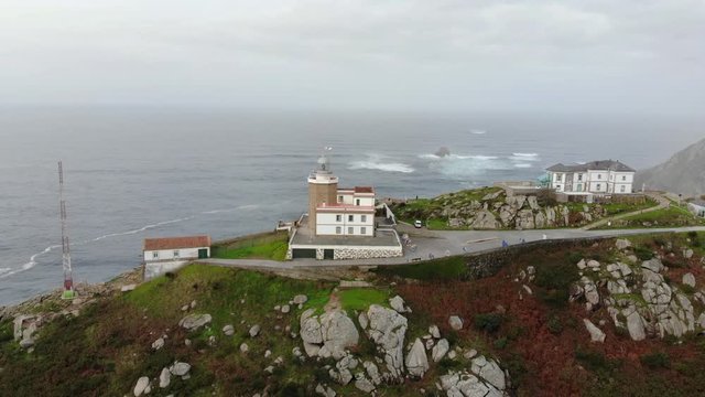 The lighthouse is the destination of pilgrims. An aerial view of the rocky coast at the Cape at Finisterre in northern Spain in Galicia. There is a lot of haze in the air and there are high waves.