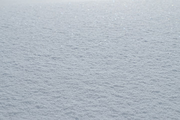 Bright sunny day with sparkling glittering fresh fallen snow.  Beautiful shiny blanket of snow texture, background and wallpaper. 