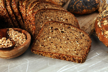 Assortment of baked bread and bread rolls and cutted bread on table background