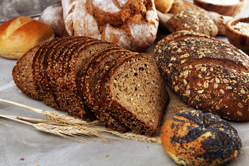 Assortment of baked bread and bread rolls and cutted bread on table background