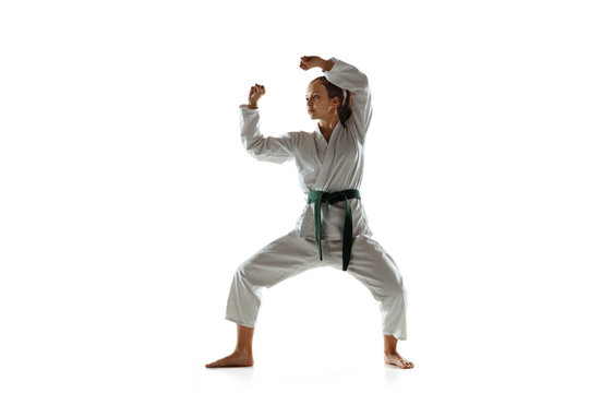 Confident junior in kimono practicing hand-to-hand combat, martial arts. Young female mongol fighter with green belt training on white studio background. Concept of healthy lifestyle, sport, action.