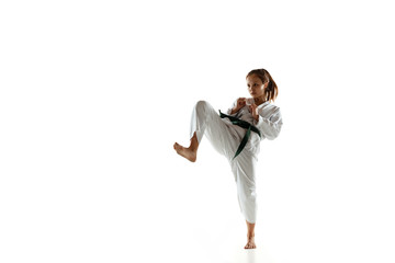 Confident junior in kimono practicing hand-to-hand combat, martial arts. Young female mongol...