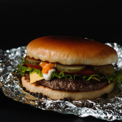 Big sandwich - hamburger burger with beef, pickles, tomato and tartar sauce on black background.