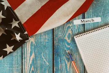 March month of calendar year United States of America flag of symbol of freedom and democracy with blank notepad and pen on office wooden table