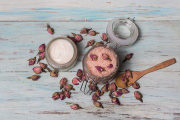Facial cream and rose bath salt, top view, on a light wooden background. Cosmetics and natural medicinecine