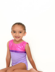 small latin girl doing gymnastics with white background and purple sportswear