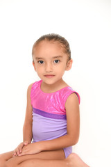 small latin girl doing gymnastics with white background and purple sportswear