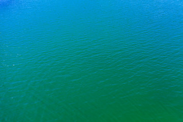 aerial view of the texture of the surface of turquoise water with sun reflections