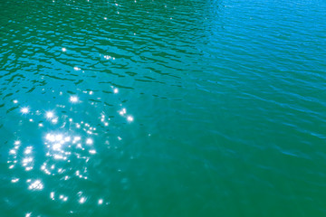 aerial view of the texture of the surface of turquoise water with sun reflections