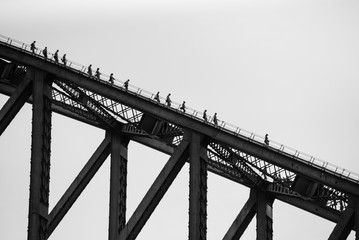 SYDNEY HARBOUR BRIDGE, CIRCULAR QUAY, SYDNEY, NSW, AUSTRALIA. Climbers silhouettes descending the most famous Australian bridge towards the Rocks - black and white photograph