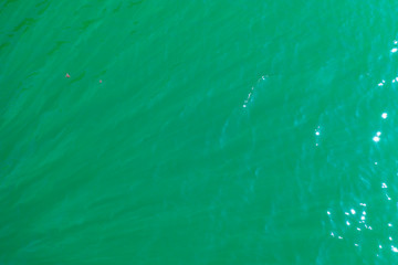 aerial view of the texture of the surface of turquoise water with sun reflections