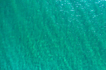 aerial view of the texture of the surface of turquoise water with sun reflections