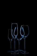 Glassware selection with wine, champagne and liquour glasses toned in classic blue on the dark background.. Fine cristal glassware concept. Vertical