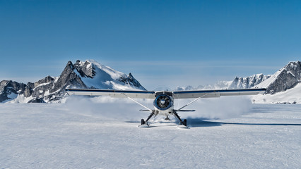 Small bush plane with skiis landing on an snow field