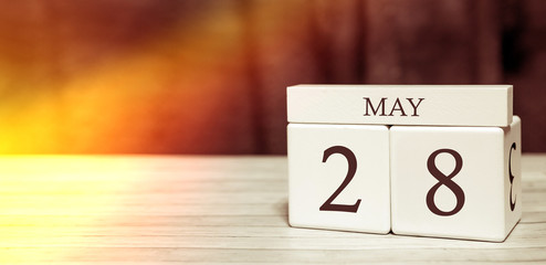 Calendar reminder event concept. Wooden cubes with numbers and month on May 28 with sunlight.