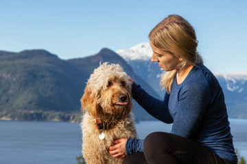 Adventurous Girl Hiking on top of a Mountain with a dog during a colorful sunset. Taken on Tunnel...