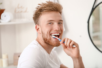 Young man brushing teeth at home