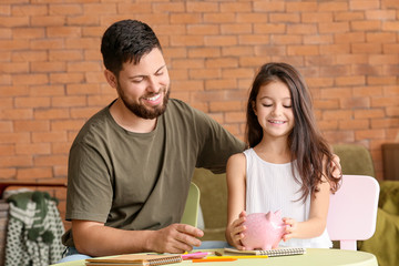 Father and little daughter with piggy bank at home