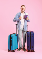 Young tourist with luggage on color background