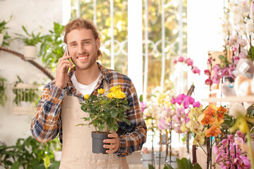 Portrait of male florist talking by phone in shop