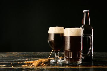 Glassware with fresh beer on table against dark background