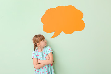 Cute little girl with blank speech bubble on color background