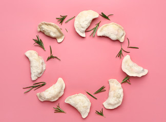 Frame made of raw dumplings with herbs on color background