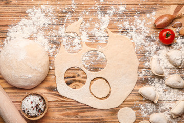 Raw dough and dumplings on wooden background