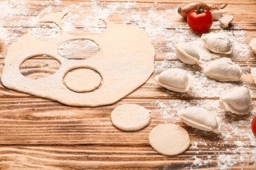 Raw dough and dumplings on wooden background