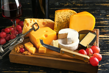Board with assortment of fresh cheeses on dark background