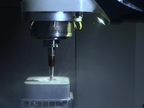 CNC Fr&auml;smaschine bearbeitet unter K&uuml;hlmittel / Emulsion einen Metallblock aus Edelstahl