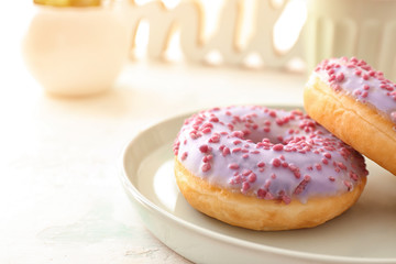 Plate with tasty donuts on light background