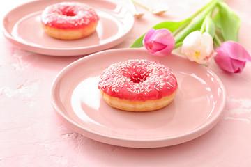 Tasty donuts and flowers on color background