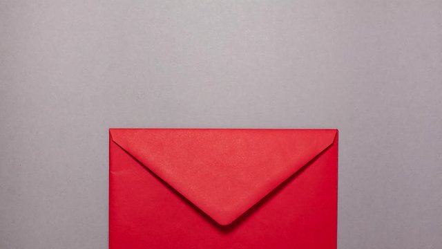 The red paper envelope with pink hearts inside on gray background. Flat lay top view stop motion animation. Valentines day and invitation concept
