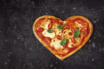Delicious heart shaped Italian pizza on black background