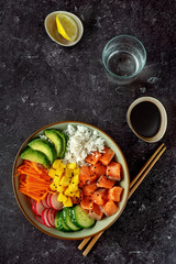 Fototapeta na wymiar Top view of poke bowl with salmon on black background