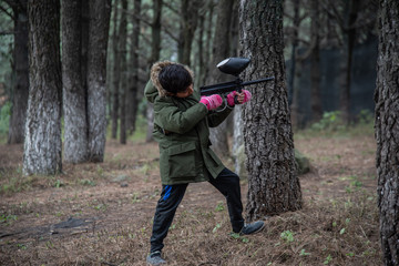 Fototapeta premium boy with green jacket playing gotcha in the woods among trees