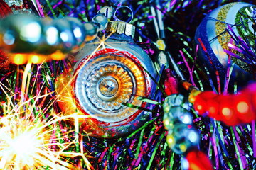 Fototapeta na wymiar Vintage silver Christmas ball on blue Christmas tinsel between threads of retro glass beads with yellow sparks fireworks. Bright beautiful colorful new year wallpaper. Selective focus