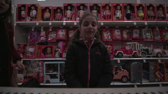 Adorable 8 years Girl With Brown Long Hair select Doll in toy section of Supermarket