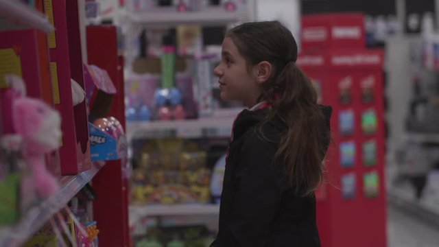 Adorable 8 years Girl With Brown Long Hair select Doll in toy section of Supermarket