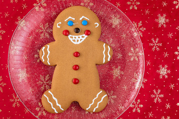 Large gingerbread cookie on a glass platter, red fabric background with gold snowflakes