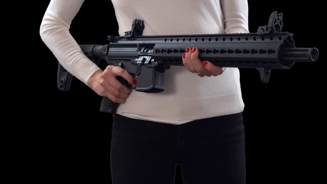 Woman holding assault rifle, adjusting and pointing on black background