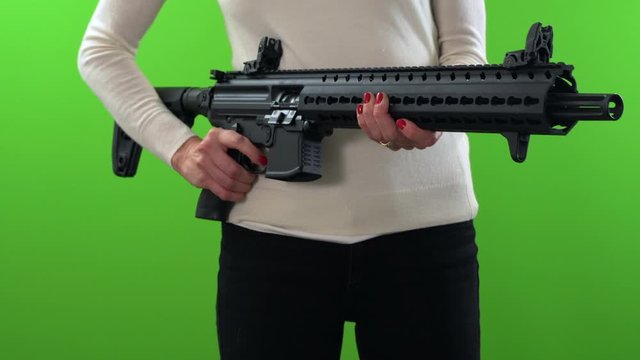 Woman holding assault rifle, adjusting and pointing on green screen background