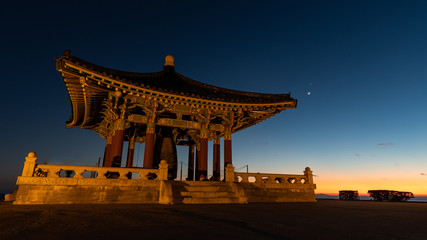 An Asian Temple At Sunset With A Crescent Moon and Venus Visible