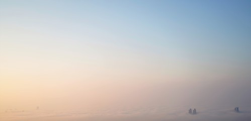 fog over the city and sun light over white clouds