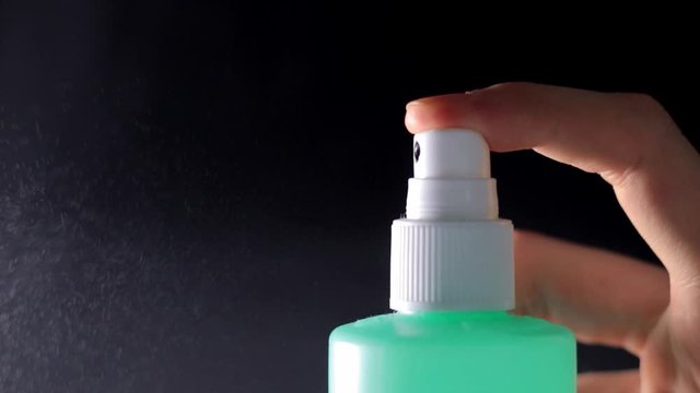 Green spray bottle sprays aerosol / side view / 40% slow-motion