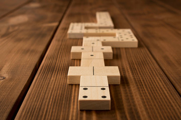 Playing dominoes on a wooden table. Leisure games concept. Selective focus.